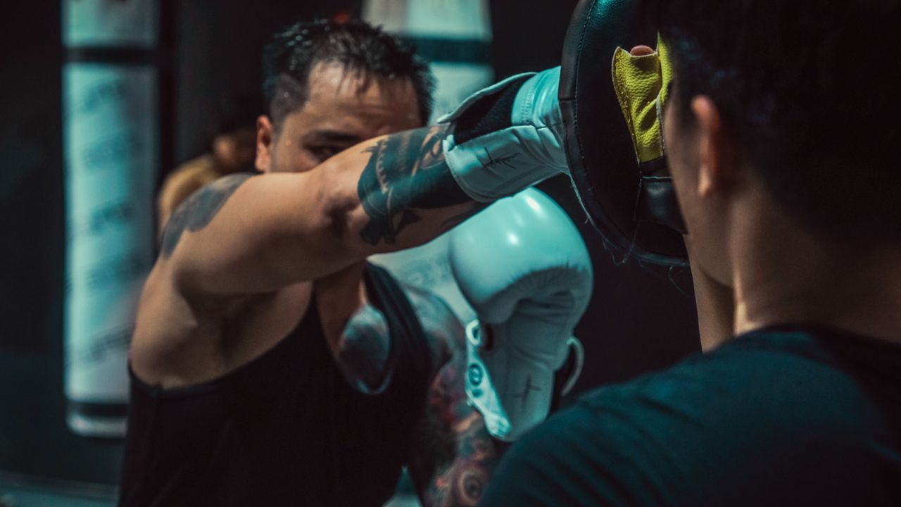 An intense boxing training session with gloves, focusing on punches inside a gym setting.
